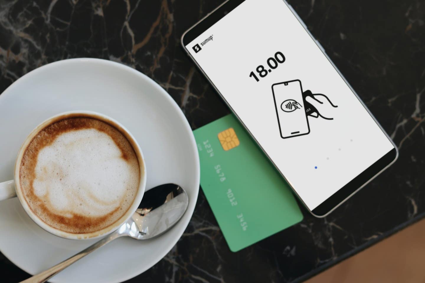 Smartphone con schermo di pagamento accanto a caffè e carta di credito.